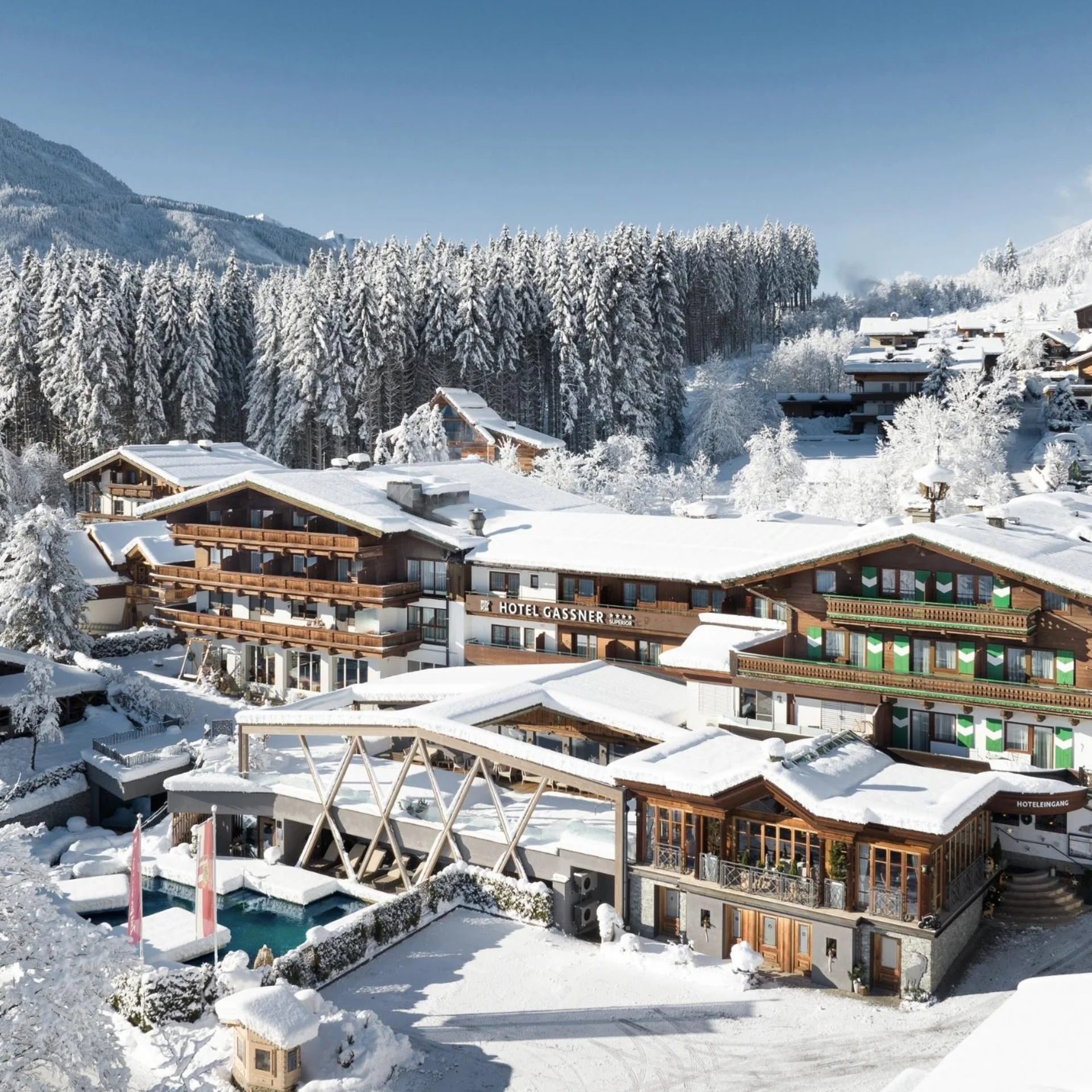 Abseits der Piste Verschneites Hotel und Dorf in den Bergen mit Bäumen und klarem Himmel
