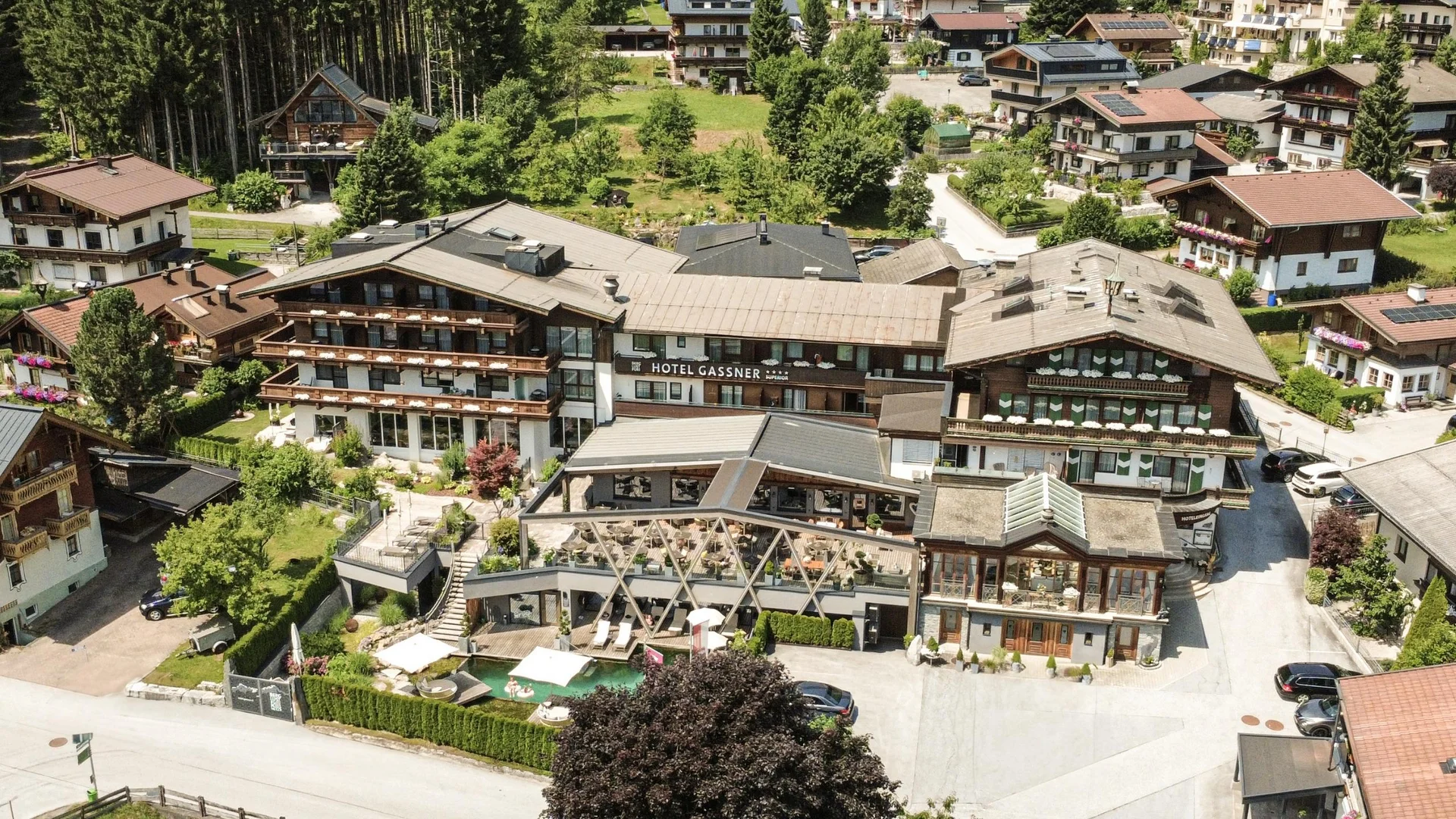 Lage + Anreise Luftaufnahme von Hotel Gassner und umliegenden Gebäuden in einer Alpenlandschaft