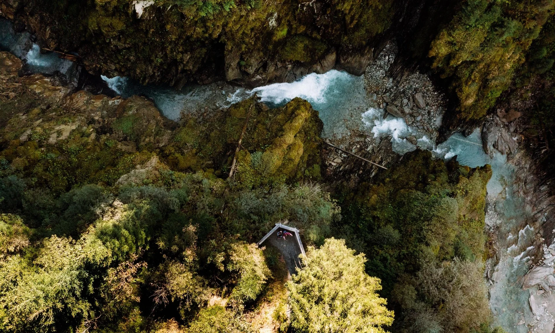 Wanderhotel Luftaufnahme eines Flusses, der von bewaldeten Felsen eingeschlossen ist