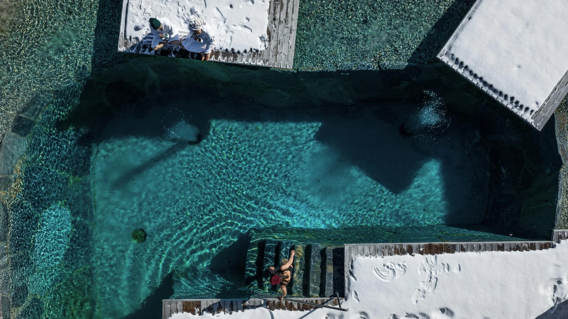 Saunawelt Menschen entspannen auf Liegen neben klarem Pool mit Treppe und Schatten