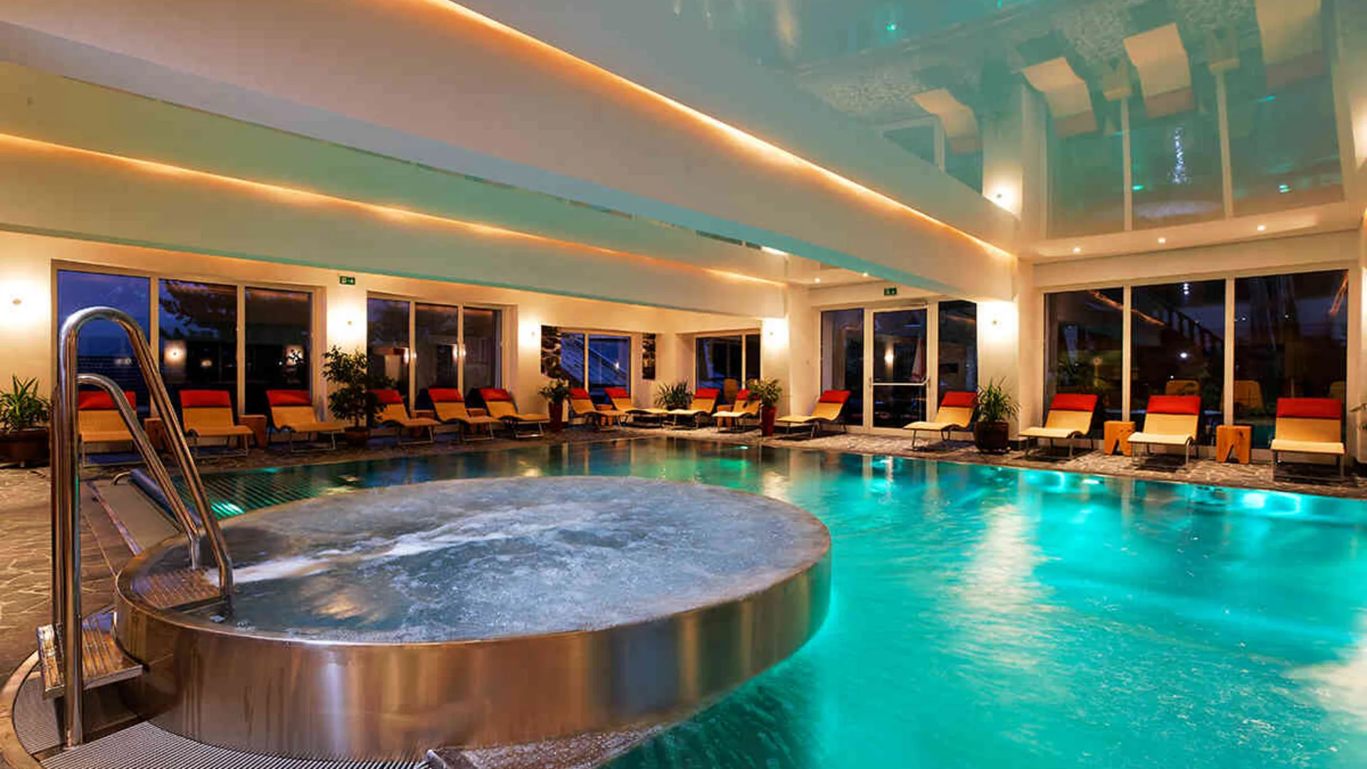 Das Hotel Innenpool mit Whirlpool und Liegestühlen in einem modernen Spa-Bereich