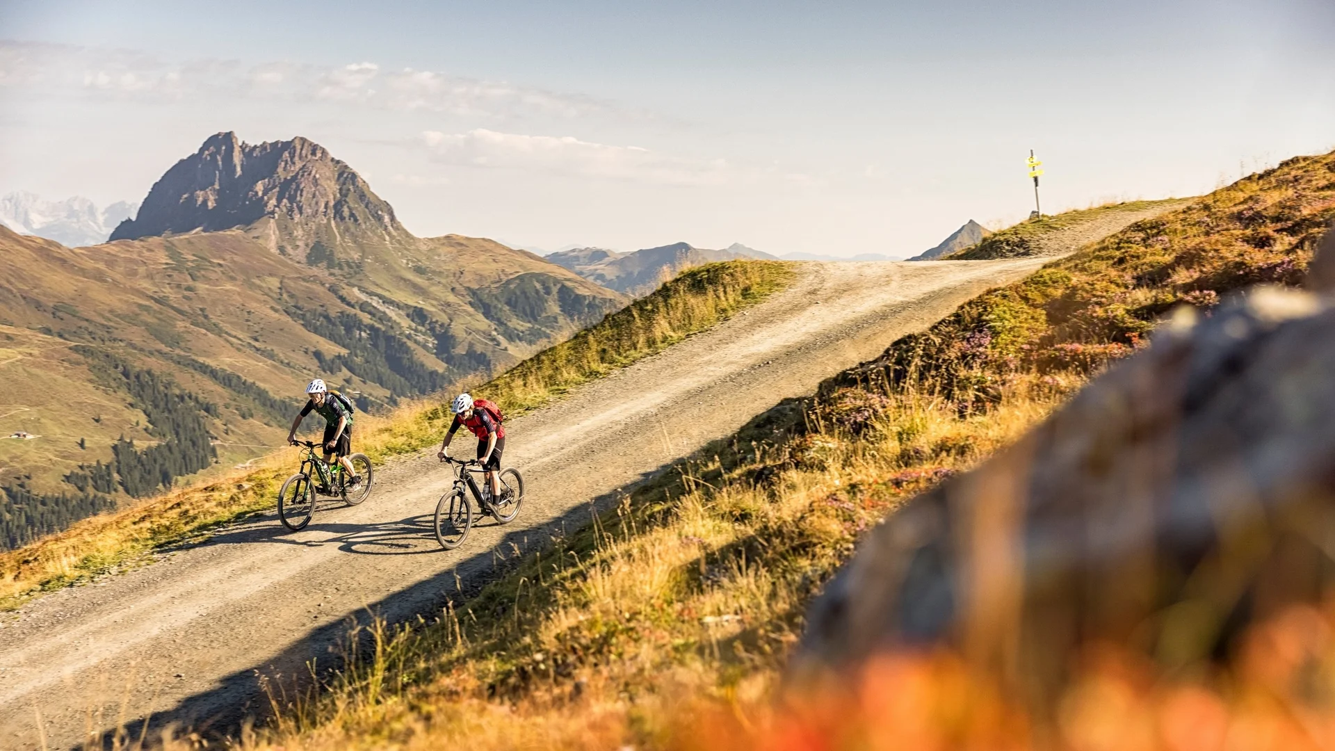 Biken Zwei Radfahrer auf Bergpfad mit Gebirge im Hintergrund