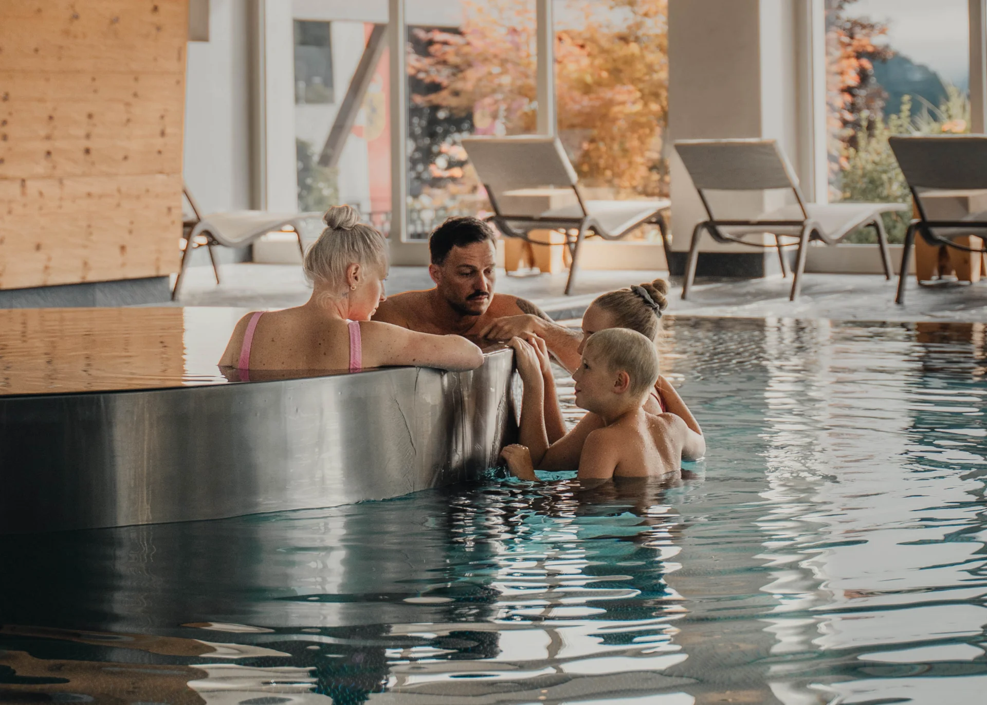 Saunawelt Familie entspannt im Hallenbad am Rande eines Whirlpool-Bereichs
