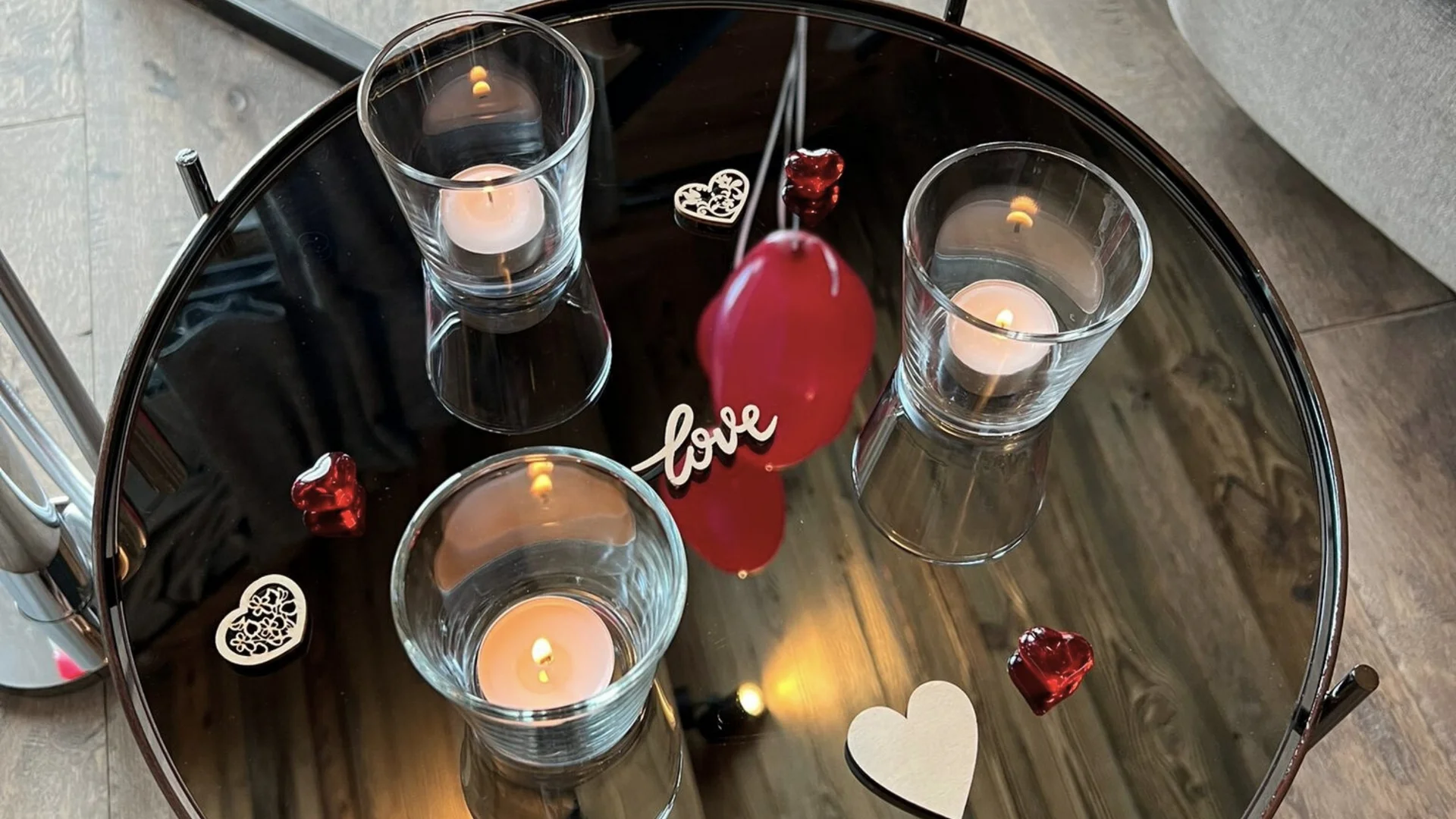 Baumhaus Spiegelnder Tisch mit brennenden Teelichtern und Dekorationen in Herzform