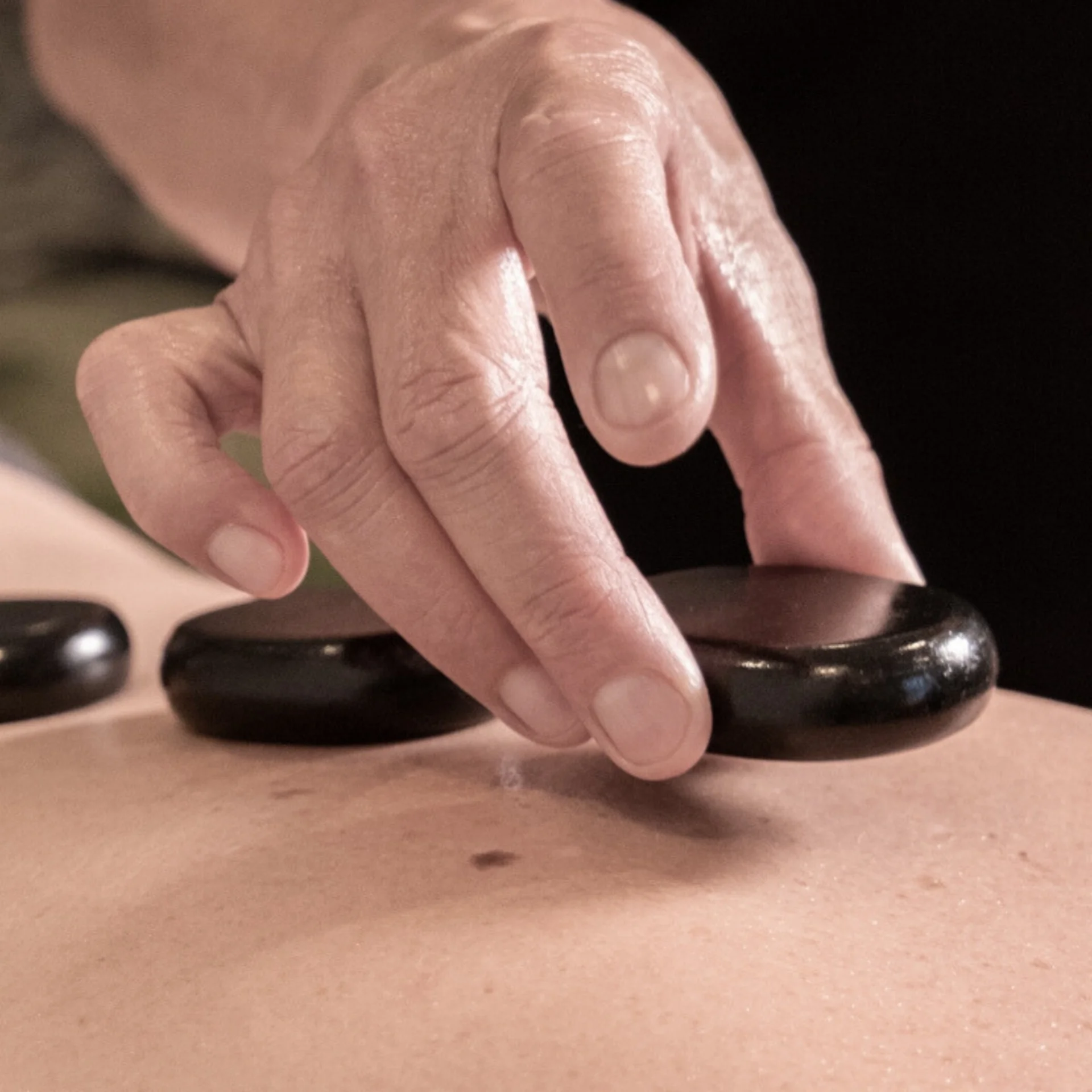 Massagen Hand legt Hot Stones während einer Massage auf den Rücken