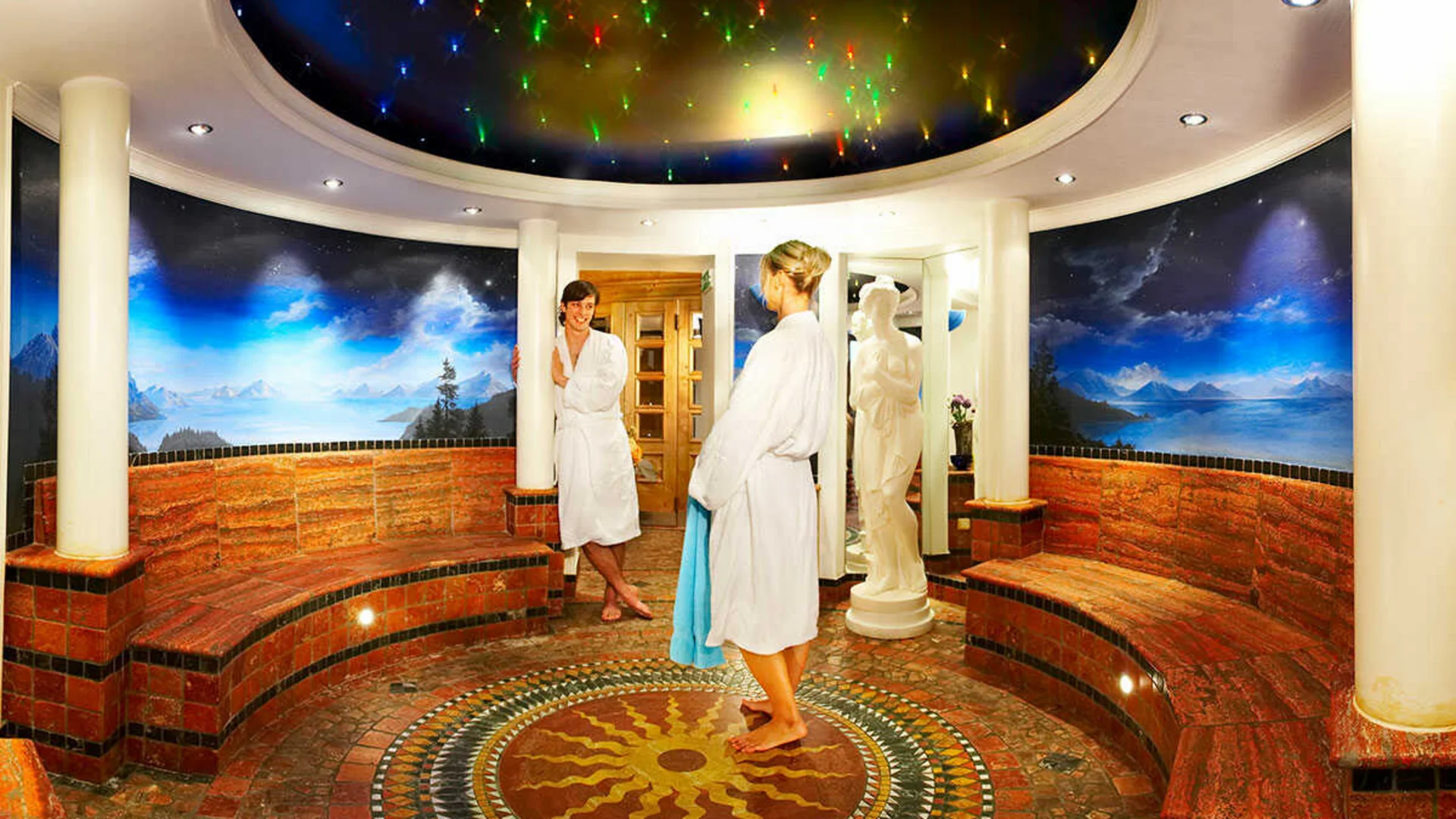 Das Hotel Runde Wellness-Lounge mit Sternenhimmel, Wandmalerei und zwei Personen in Bademänteln