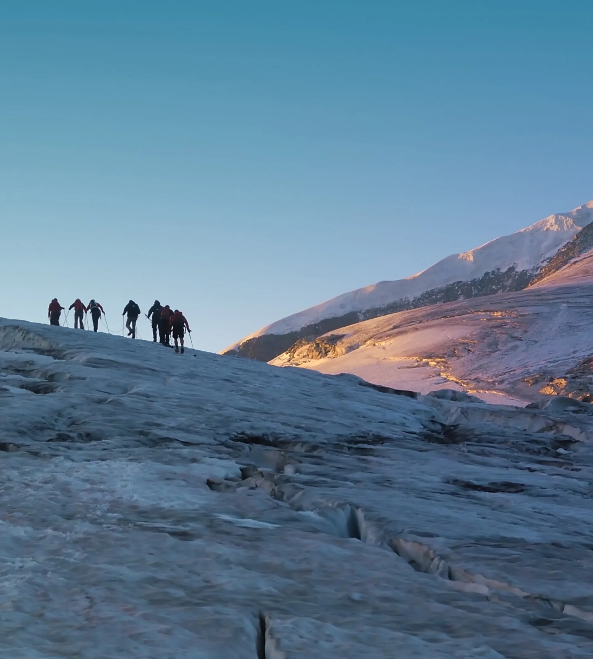Wanderservice Gruppe von Bergsteigern auf eisigem Gletscher vor spitzem Berggipfel im Morgenlicht