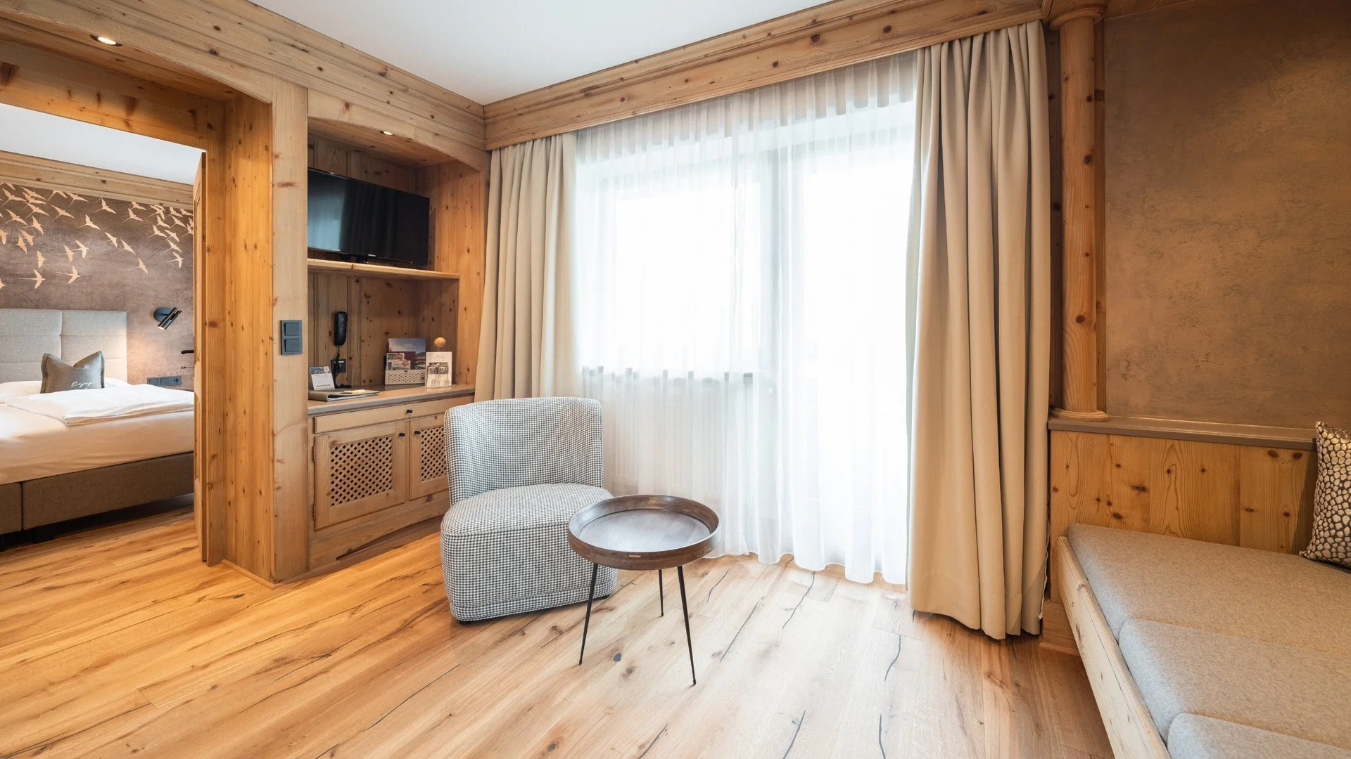 Wohnen Heller Wohnbereich mit Holzvertäfelung, Stuhl, kleinem Tisch und Blick ins Schlafzimmer