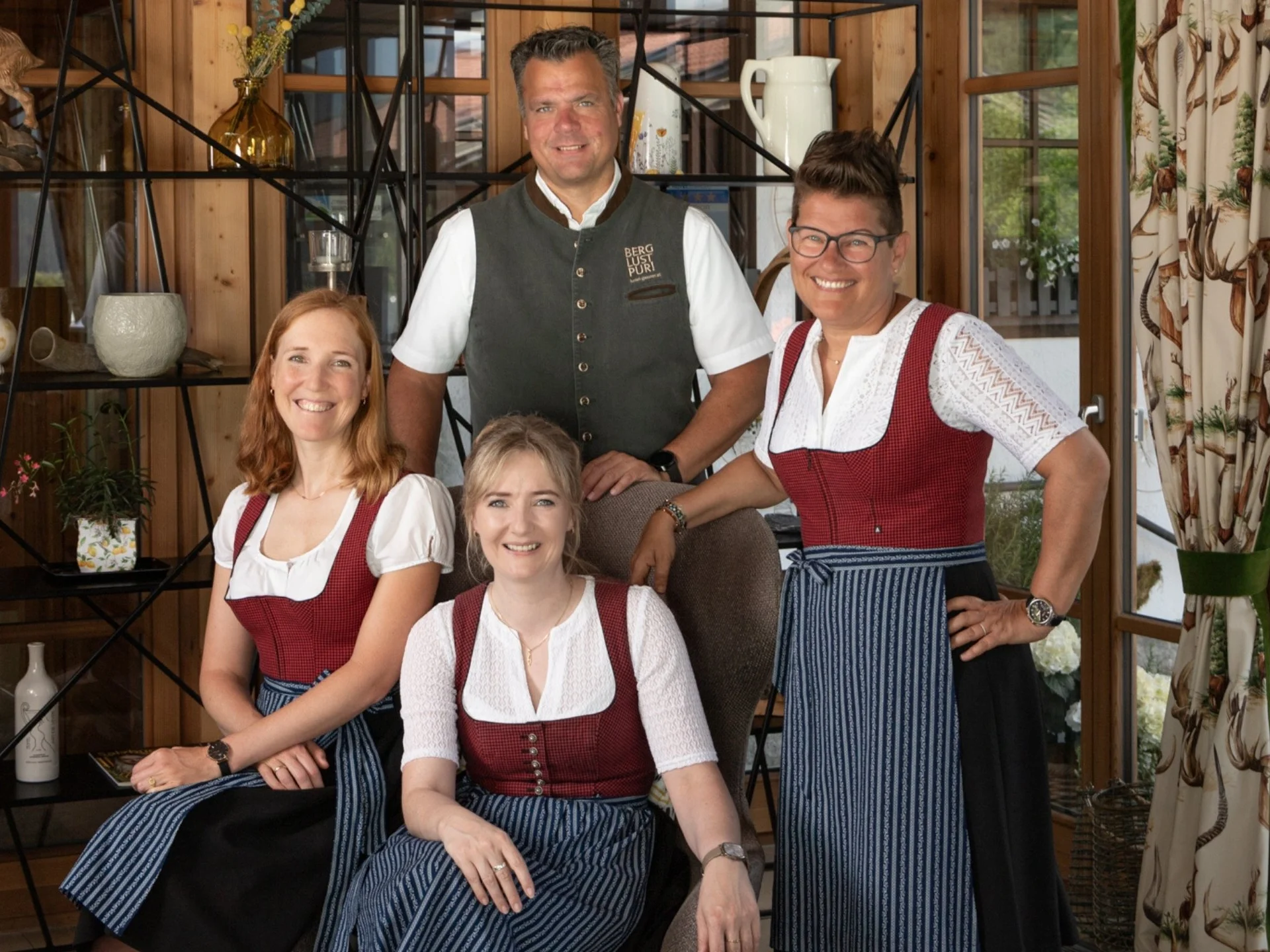 Baumhaus Vier Personen in traditioneller Tracht in einem Holzzaum eingerichteten Raum