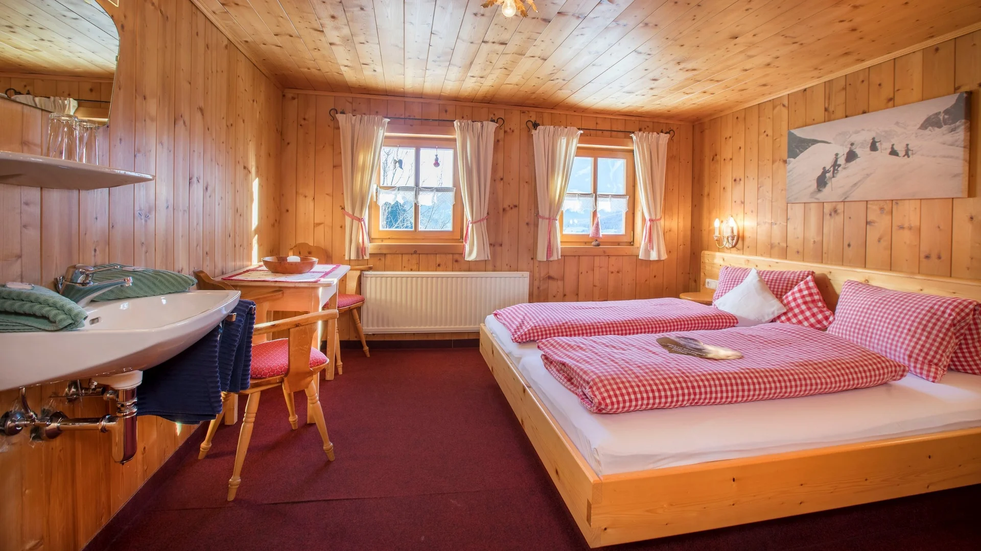 Benefits im Hotel Gemütliches Holzschlafzimmer mit roten karierten Bettdecken und weißem Waschbecken