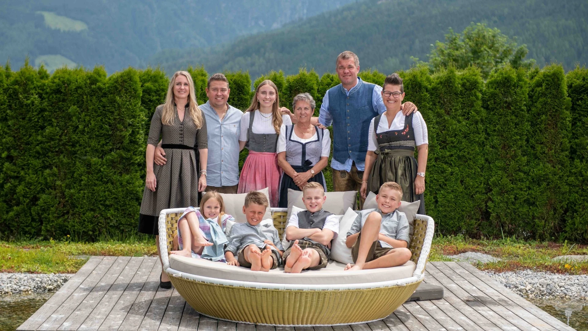 Deine Gastgeber Familienfoto der Familie Gassner im GartenSpa vor grüner Hecke und den Bergen vom Nationalpark Hohe Tauern im Hintergrund
