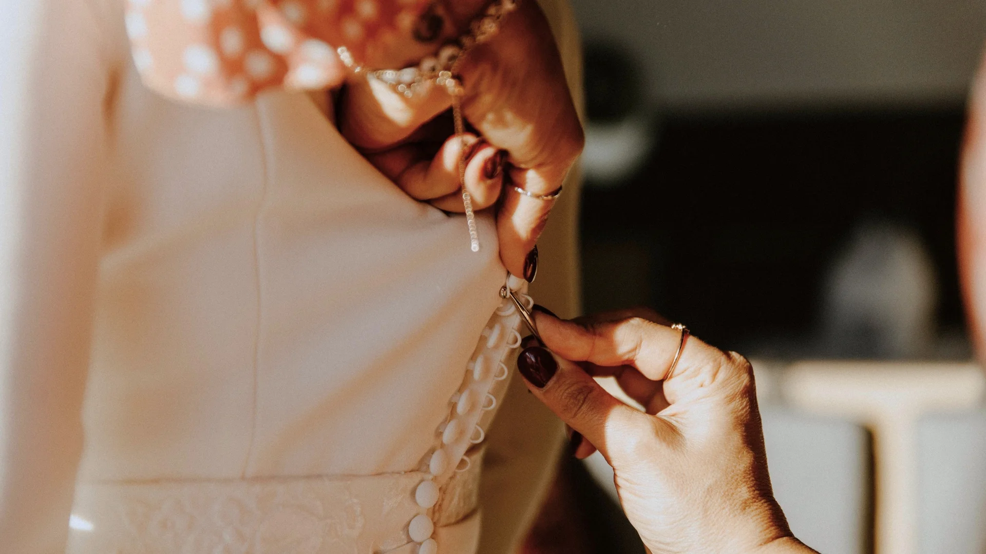 Baumhaus Hände befestigen Knöpfe an einem weißen Brautkleid