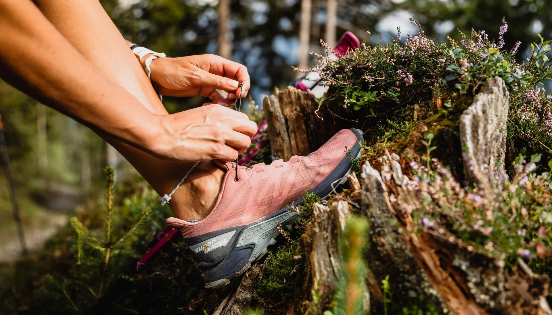 Gassner-Blog Person bindet Schnürsenkel an pinker Wanderschuh im Wald