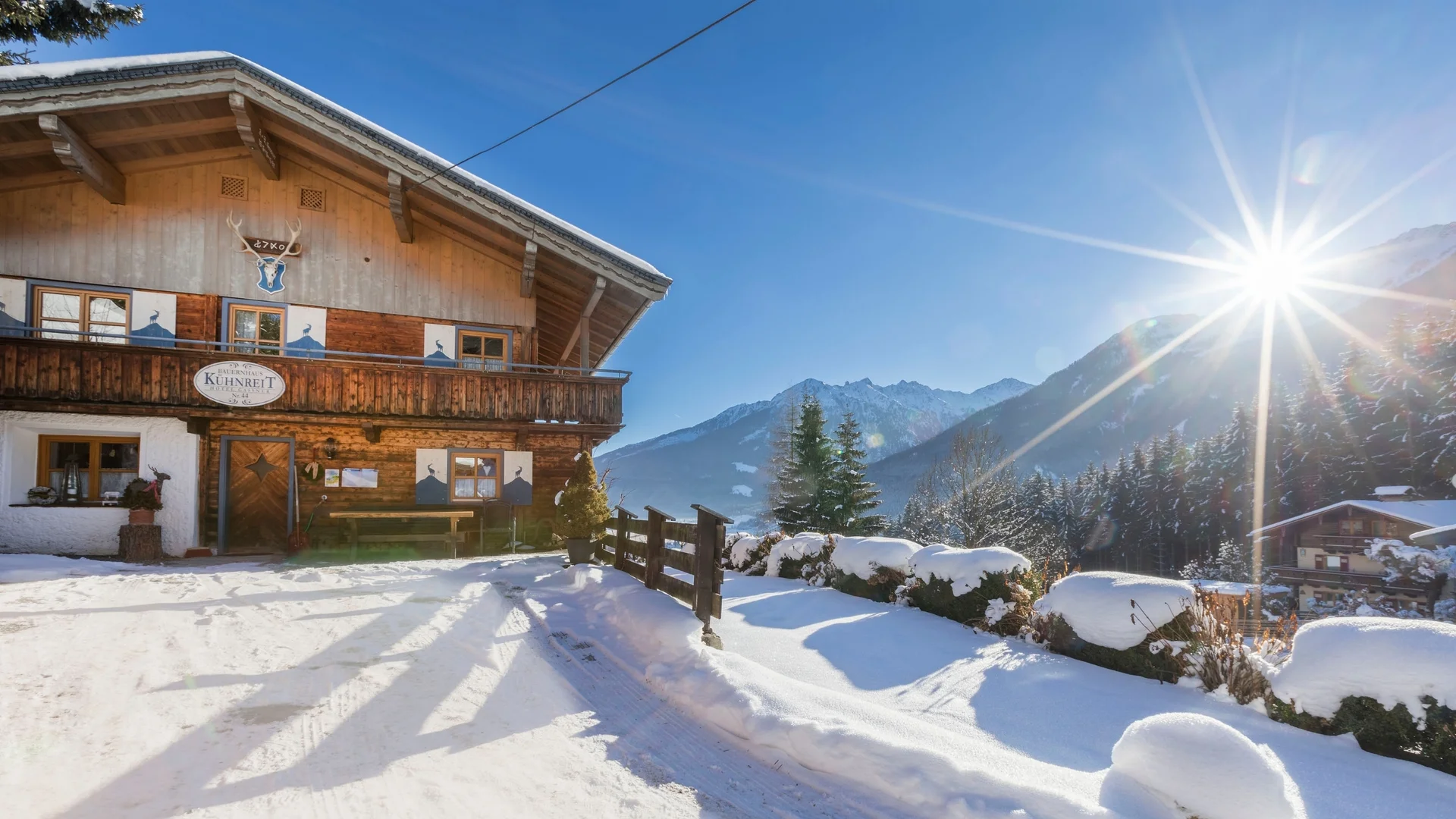 Benefits im Hotel Schneebedecktes Haus in den Bergen bei Sonnenschein und blauem Himmel