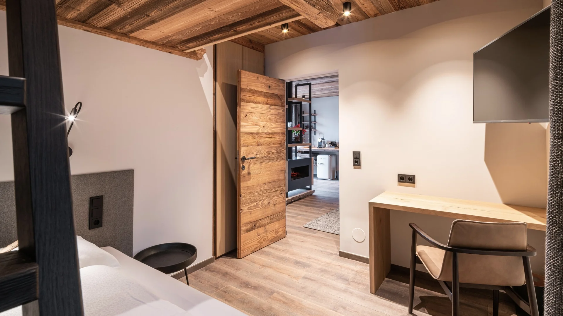 Baumhaus Kleines Zimmer mit Holzbalkendecke, offener Holztür und einfachem Schreibtisch