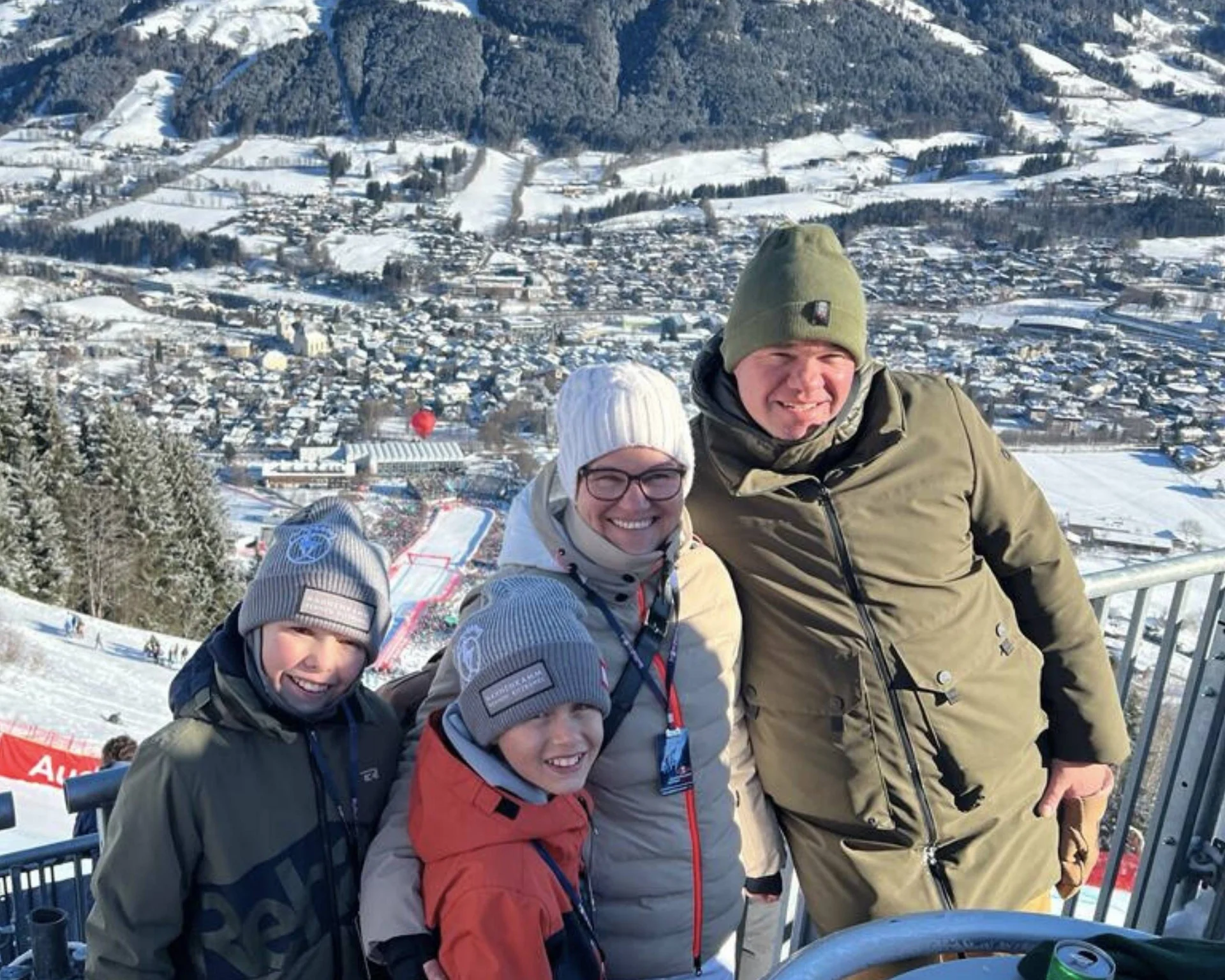 Ausflugstipps Familie in Winterkleidung beim Hahnenkammrennen in Kitzbühel vor verschneitem Bergen im Hintergrund