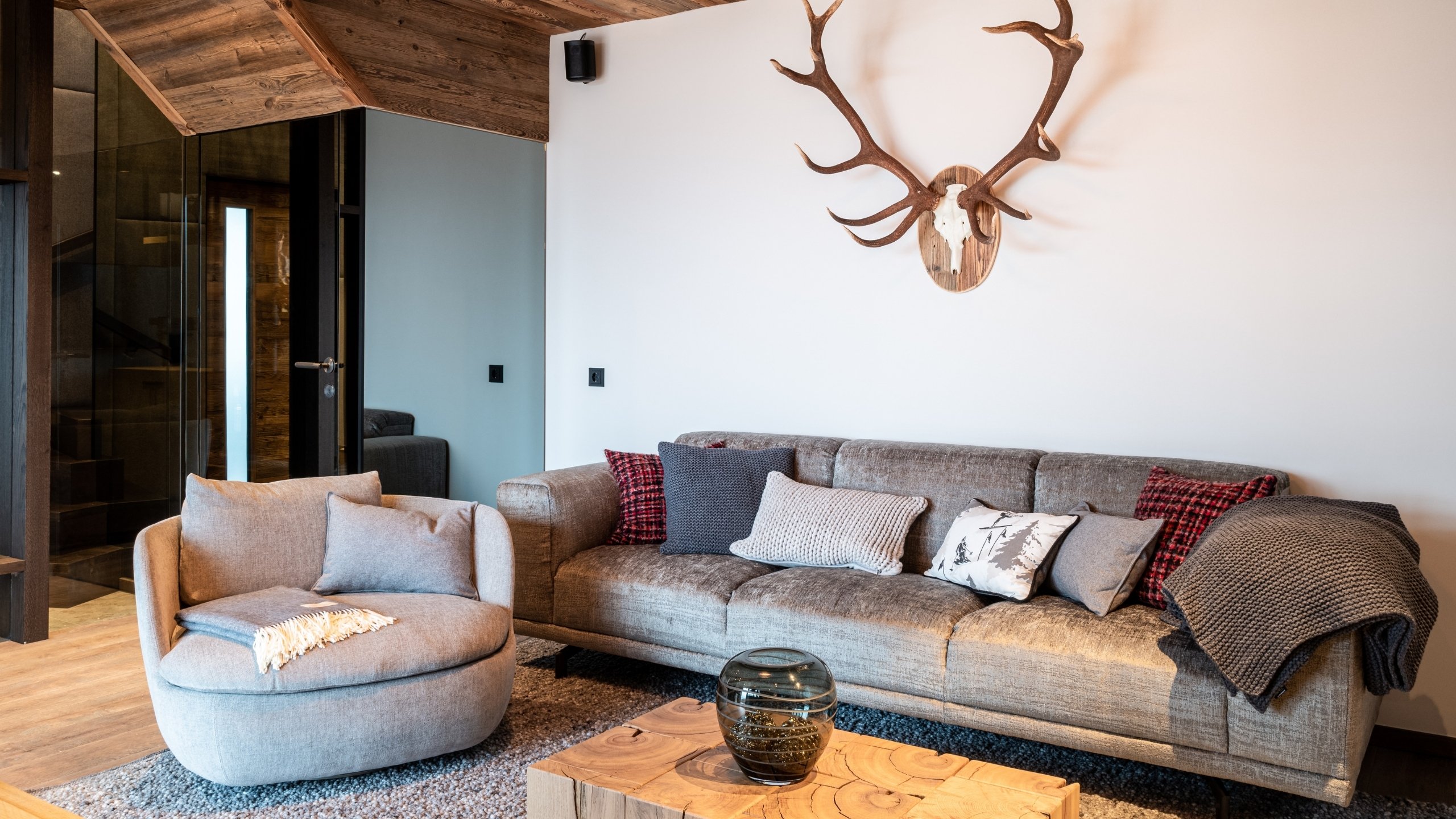 Baumhaus Gemütliches Wohnzimmer mit Sofa, rundem Sessel und Hirschgeweih an der Wand