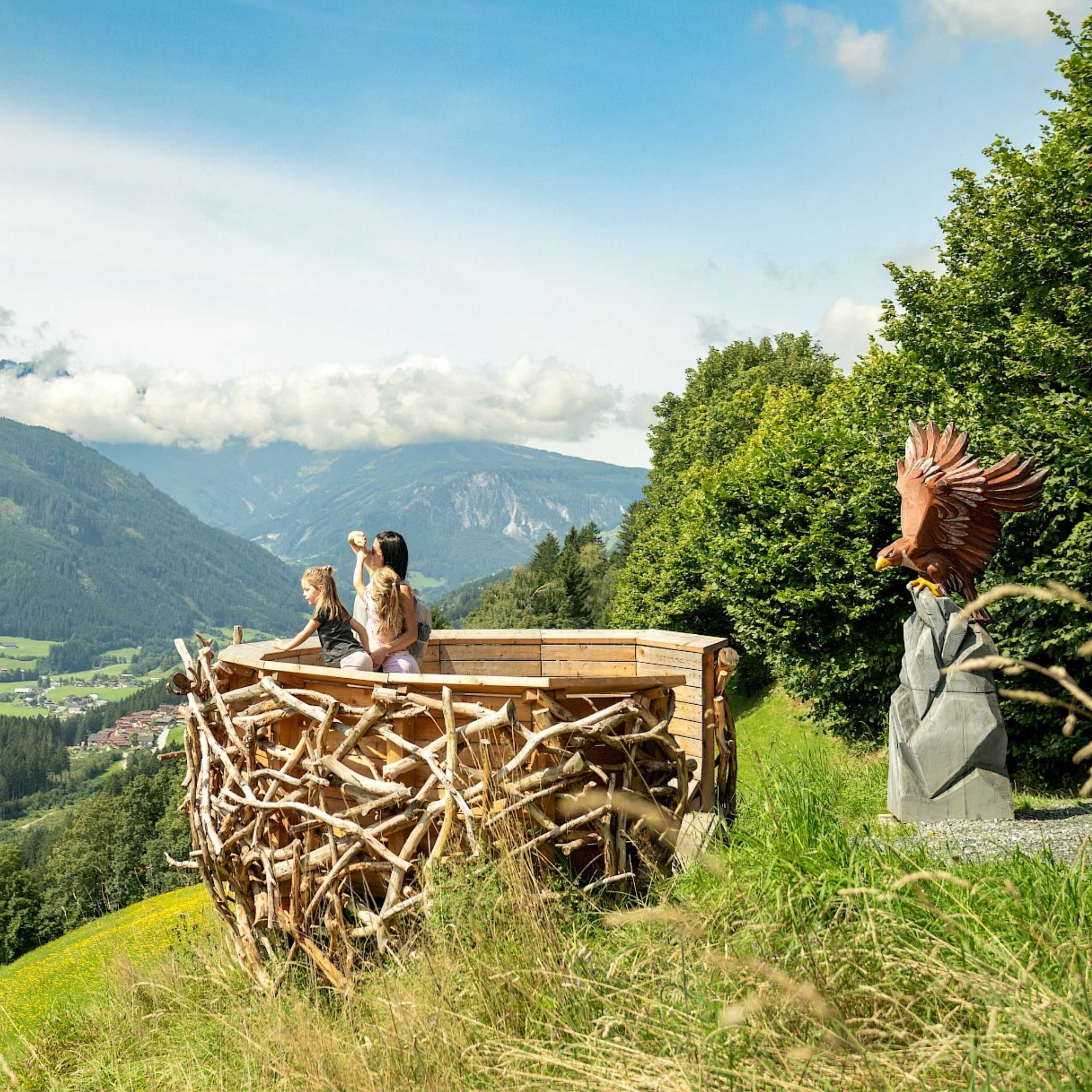 Ausflugstipps Familie auf Holzaussichtsplattform des Adler-Toni-Erlebnisweges mit Bergblick in der Wildkogel-Arena