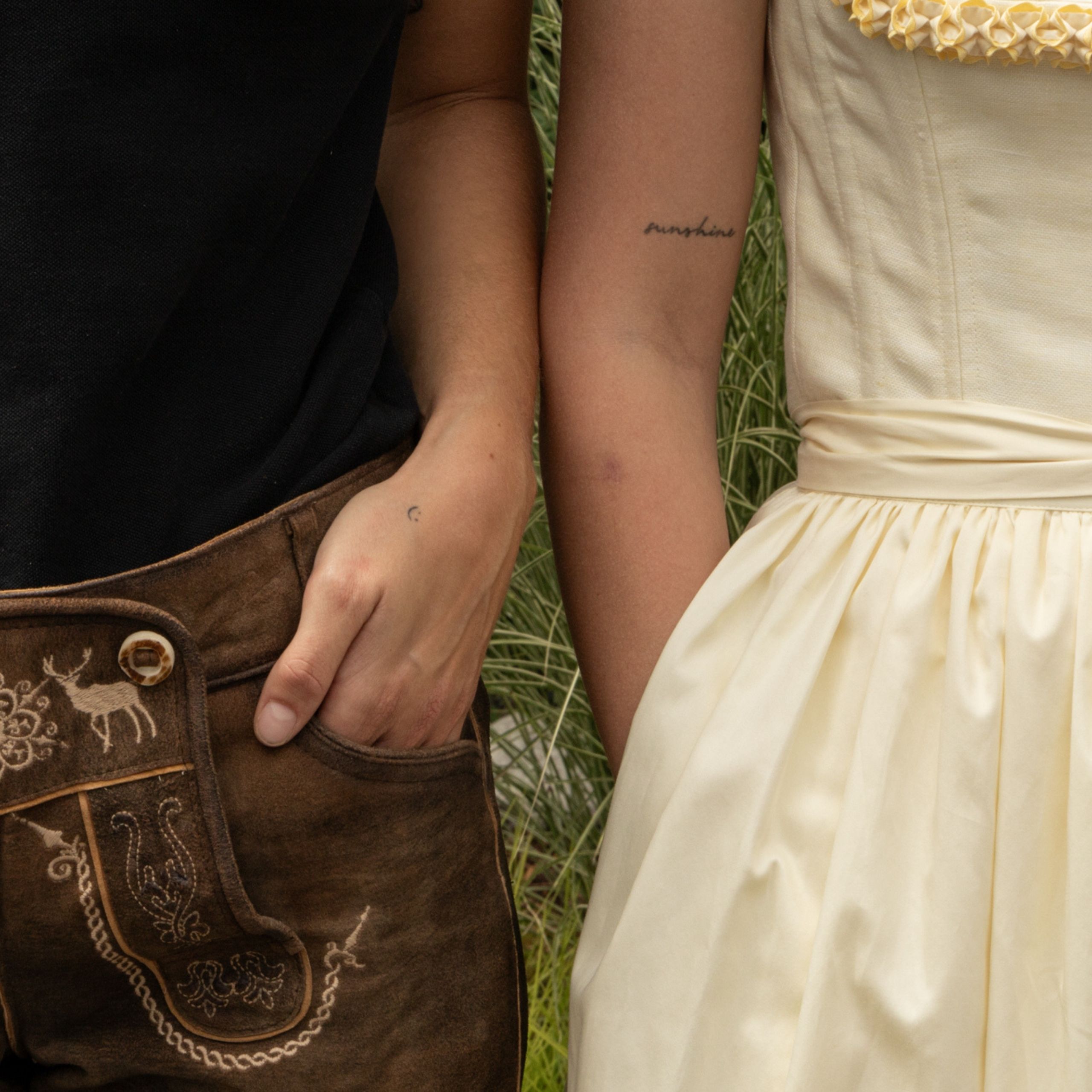 Ausflugstipps Hände von einem Trachtenpärchen in Lederhose und hellgelbem Dirndl