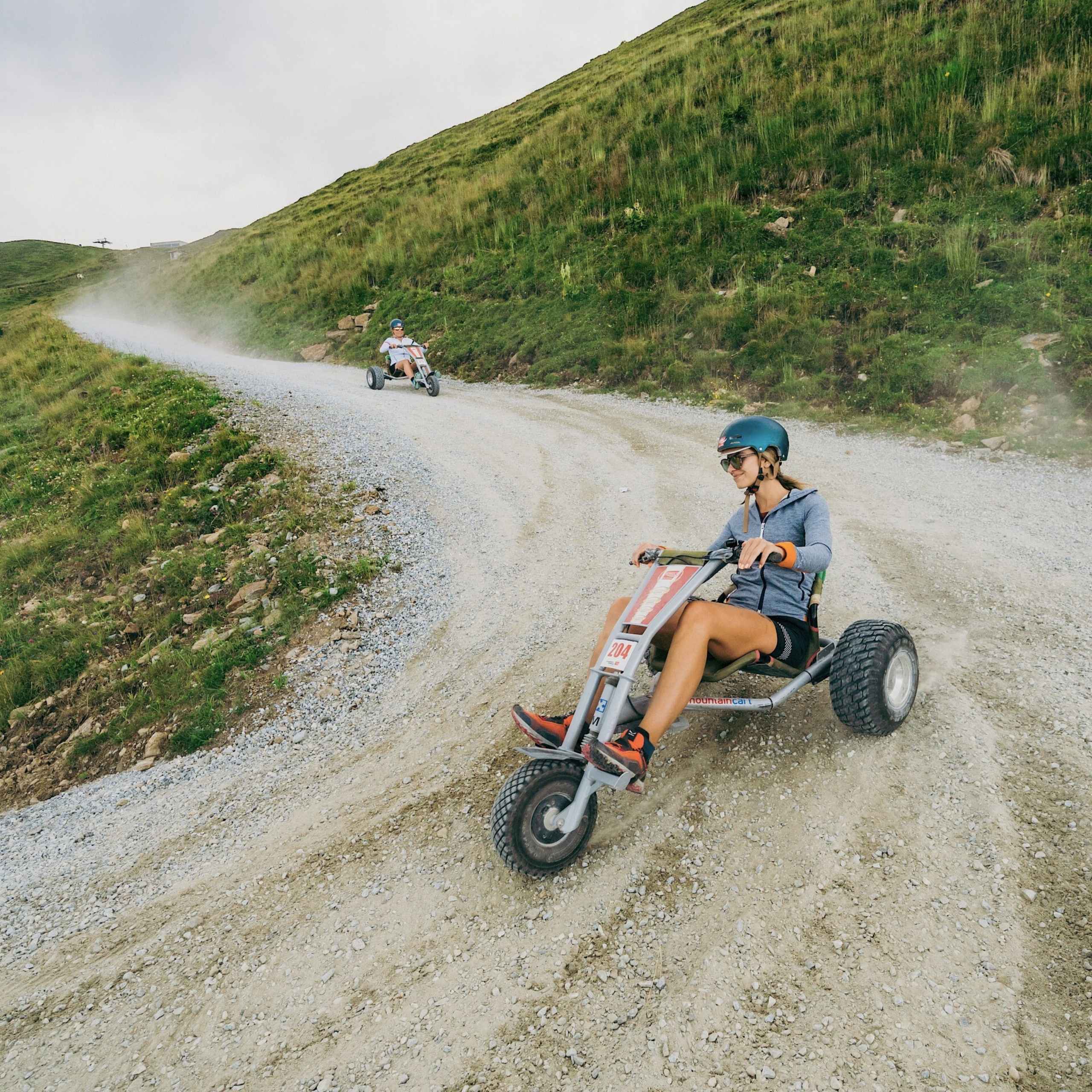 Ausflugstipps Zwei Kinder fahren auf einem Schotterweg in der Wildkogel-Arena mit den Mountaincarts bergab