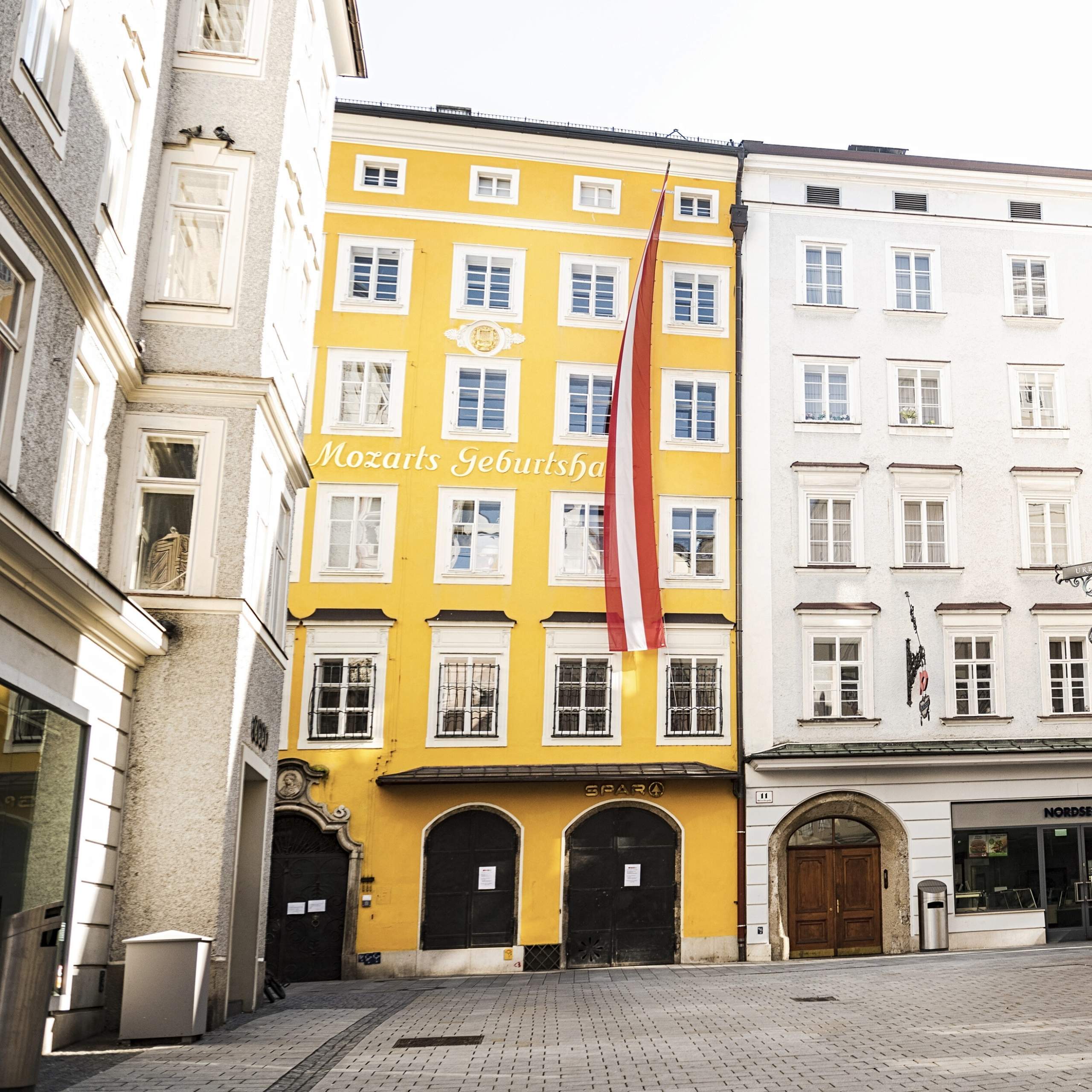 Ausflugstipps Mozarts Geburtshaus in Salzburg mit österreichischer Fahne am gelbem Gebäude in der Getreidegasse