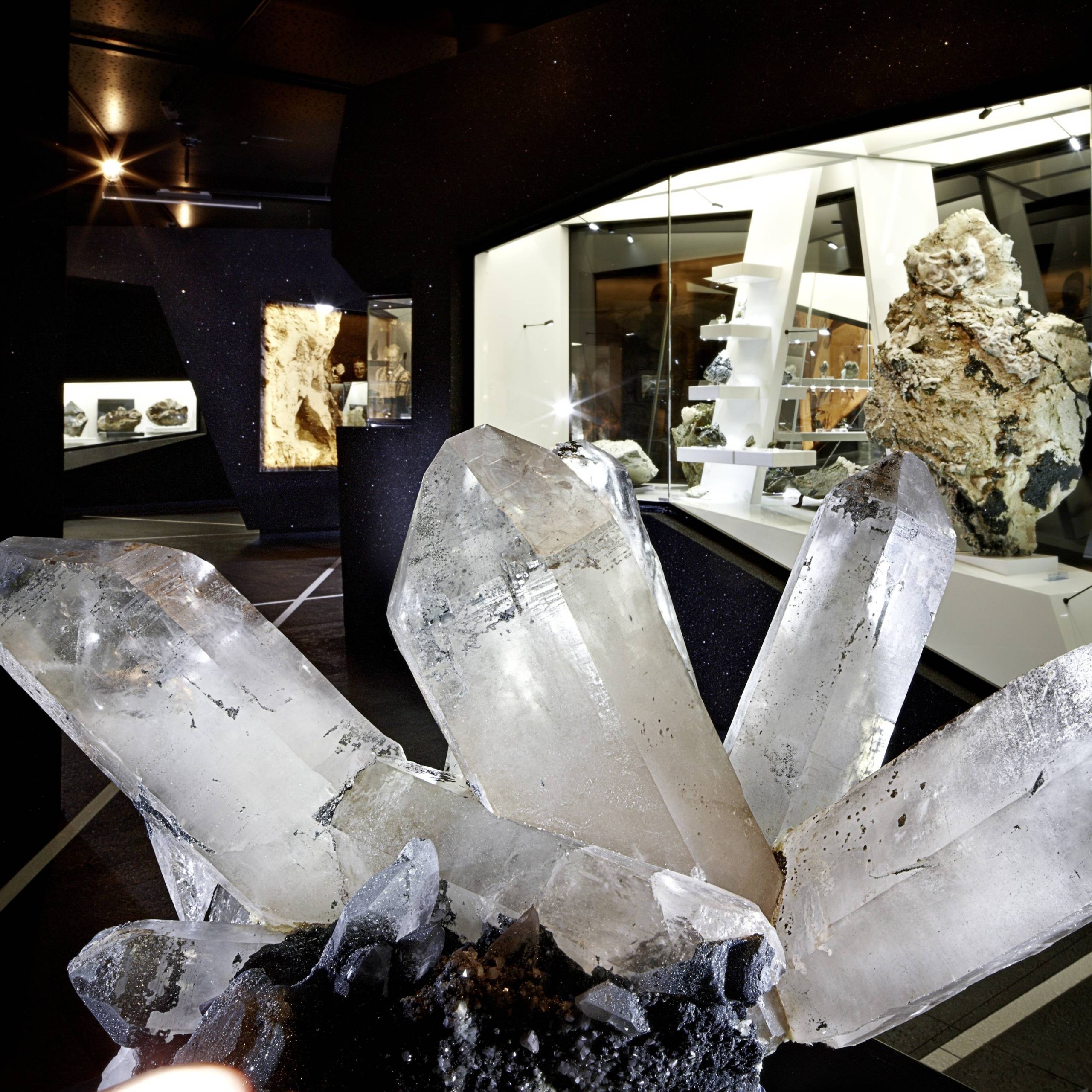 Ausflugstipps Große klare Bergkristalle in einer Museumsausstellung vom Museum in Bramberg und weiteren Mineralien im Hintergrund