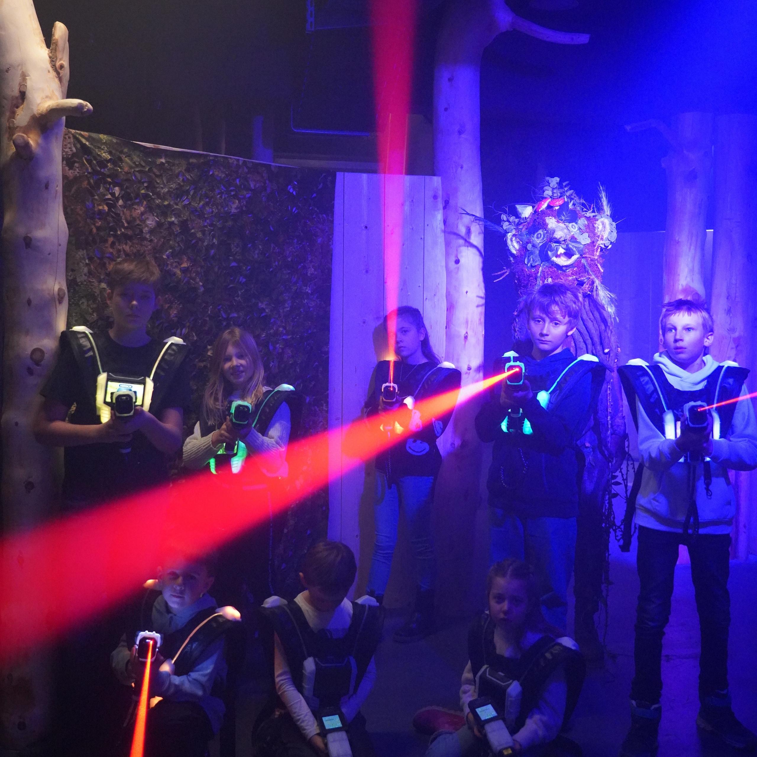 Ausflugstipps Kinder spielen im Dunkeln Laser-Tag mit roten Lichtstrahlen und Westen