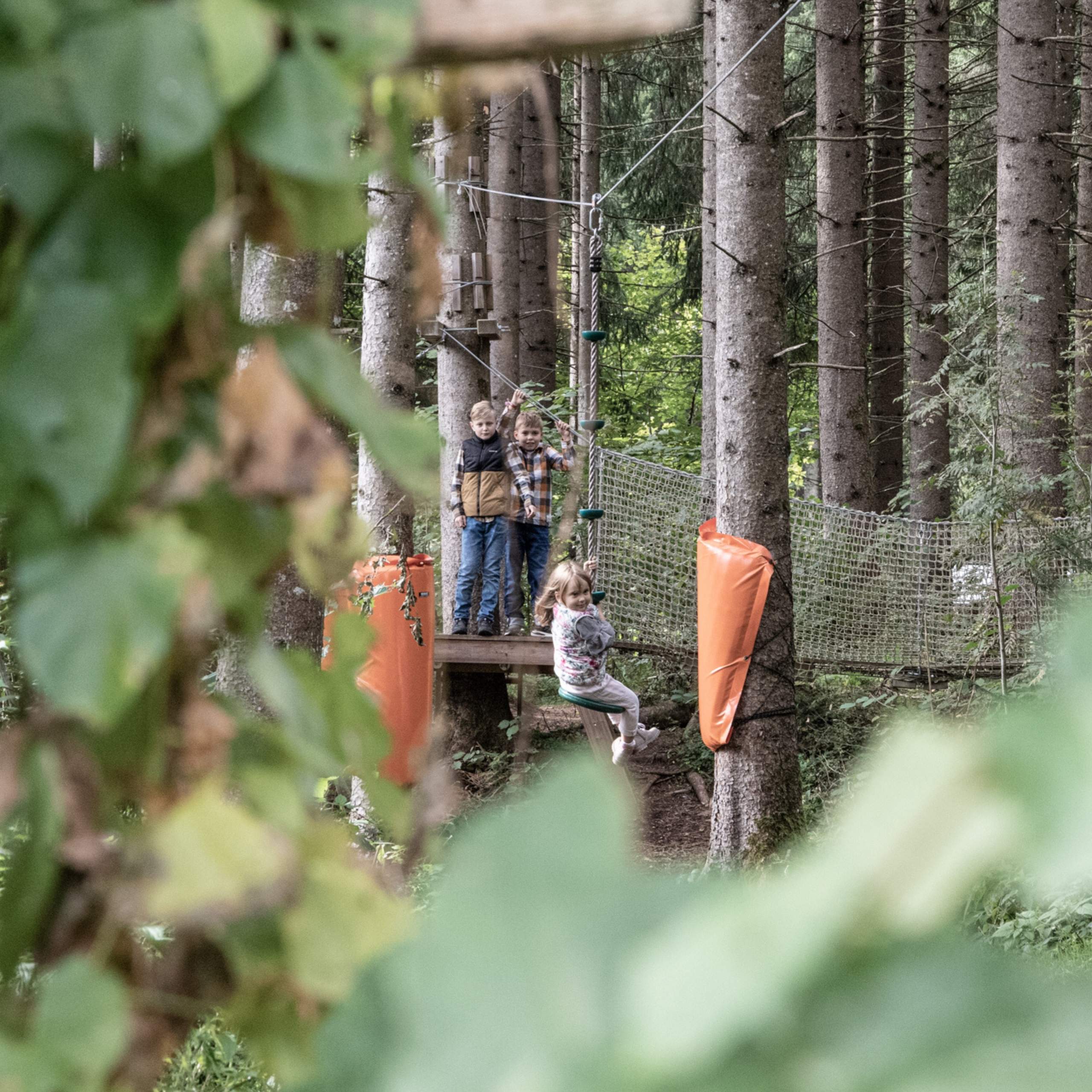 Ausflugstipps Kinder beim Klettern und Rutschen im Waldseilgarten zwischen Bäumen