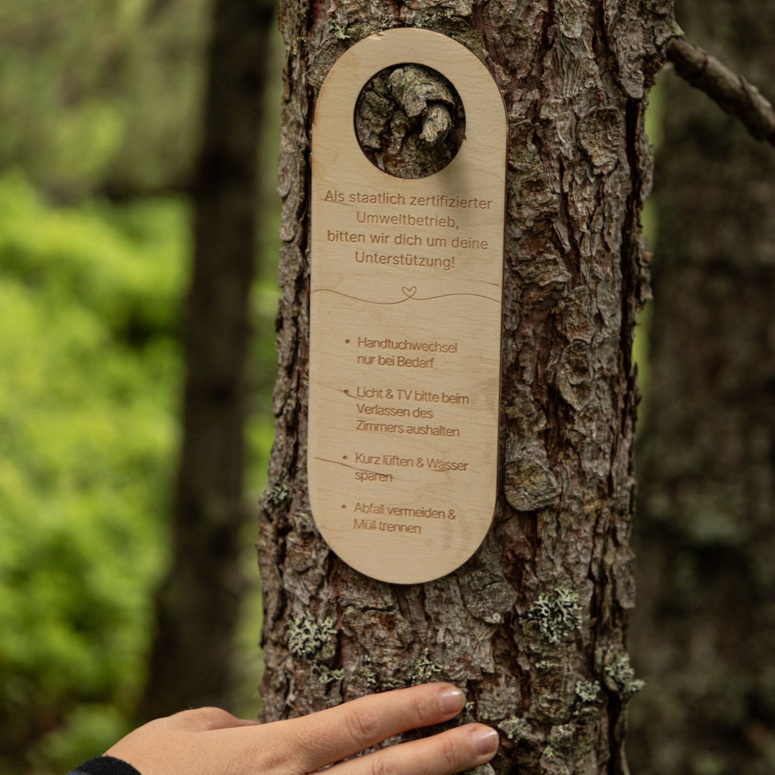 Unsere Werte Holzschild mit Umwelthinweisen an Baum befestigt, Hand berührt Baumrinde