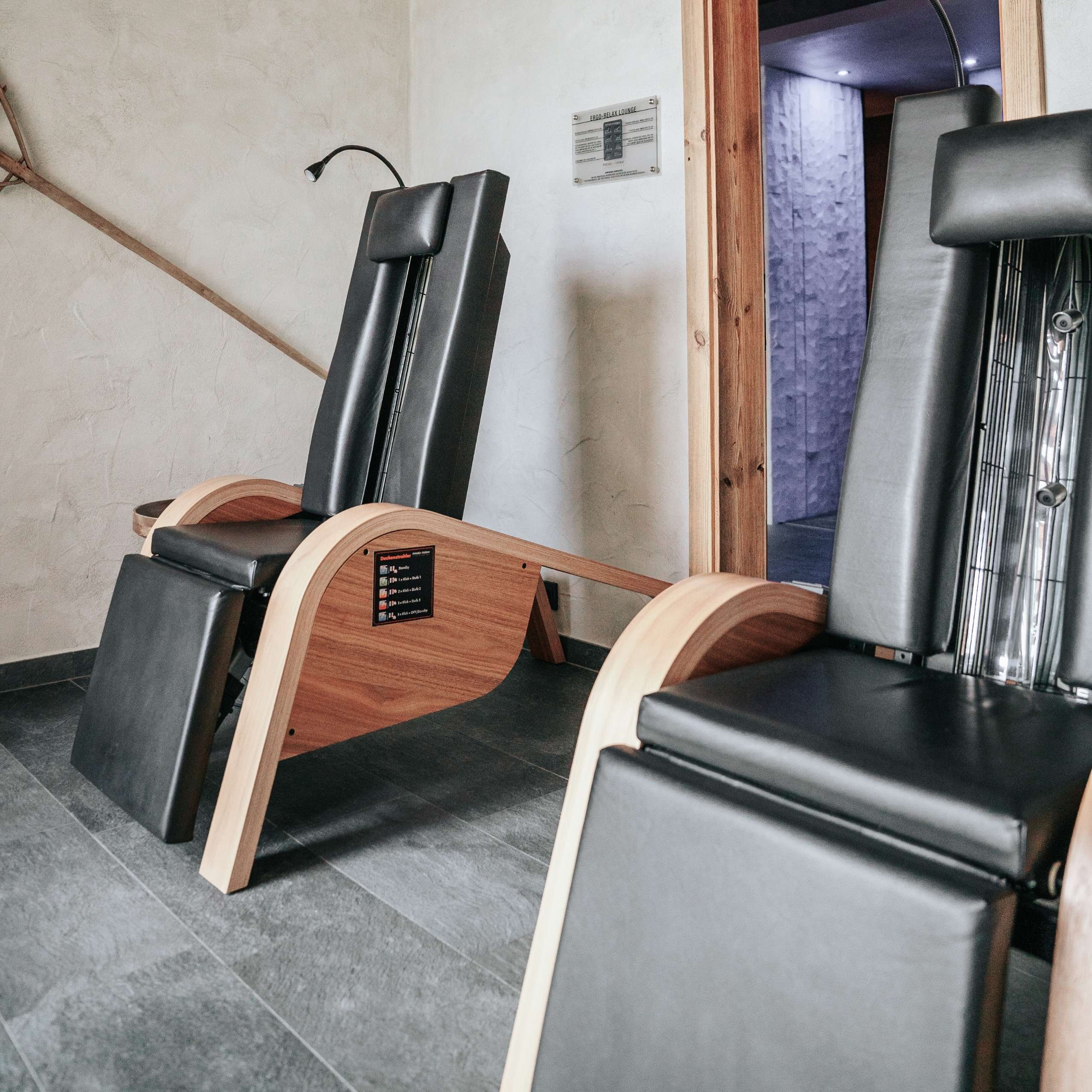 Saunawelt Zwei ergonomische Relaxsessel mit Holzrahmen und schwarzer Polsterung in Innenraum