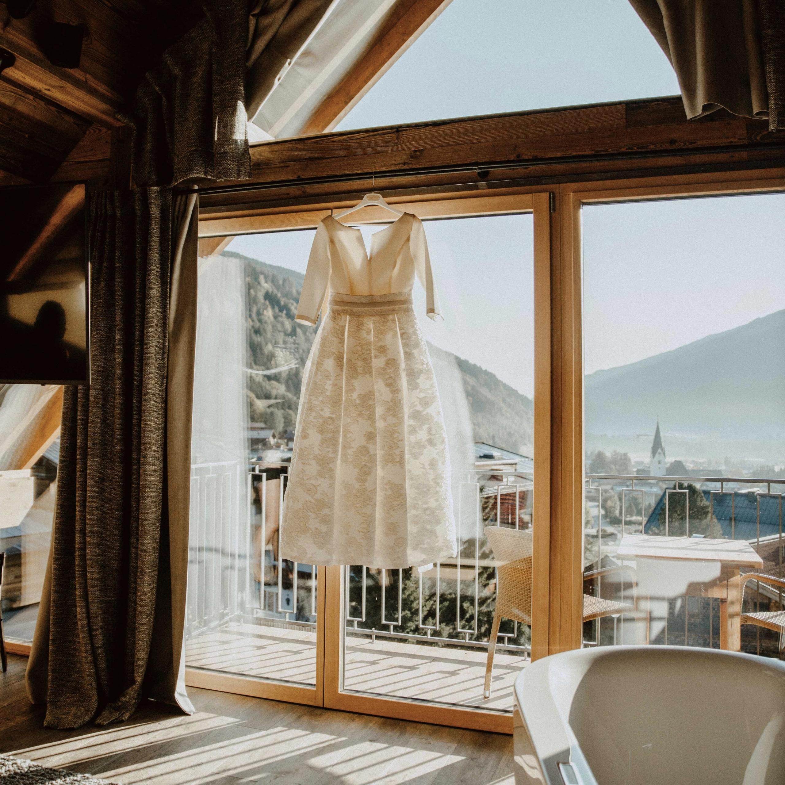 Baumhaus Brautkleid hängt vor einem großen Fenster mit Bergblick in einem Zimmer